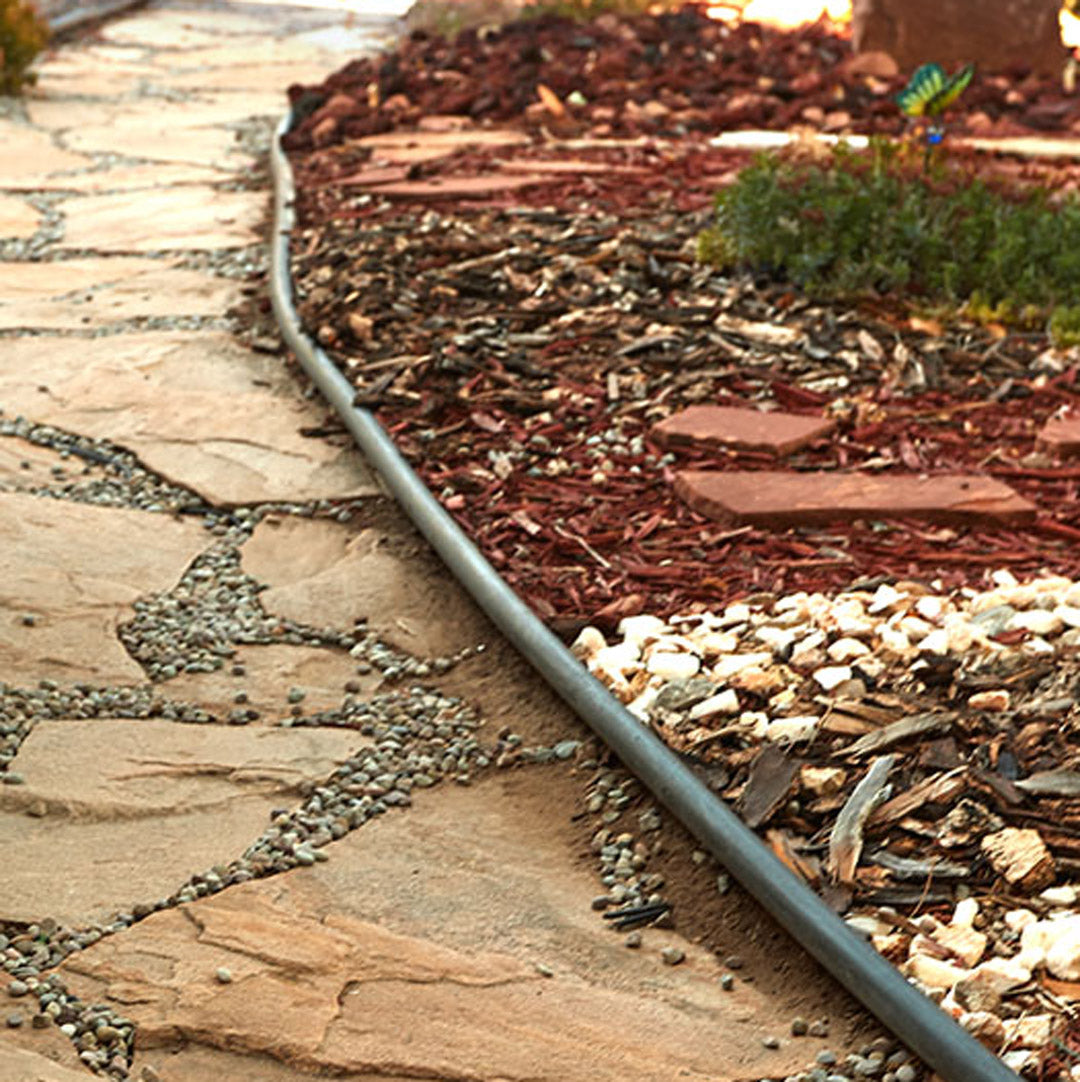 Garden bed with mulch and decorative ground cover on a stone pathway