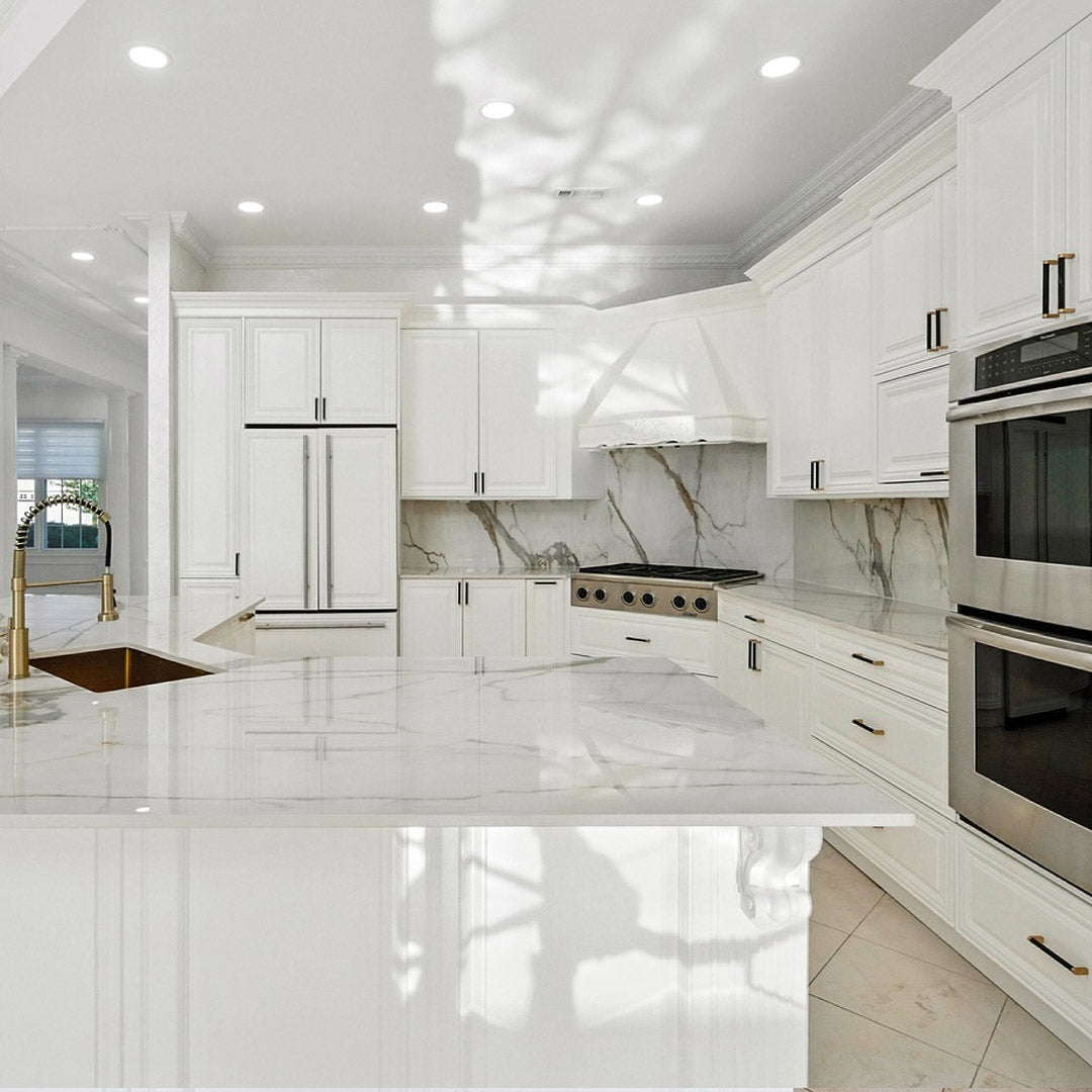 Modern white kitchen with marble countertops.