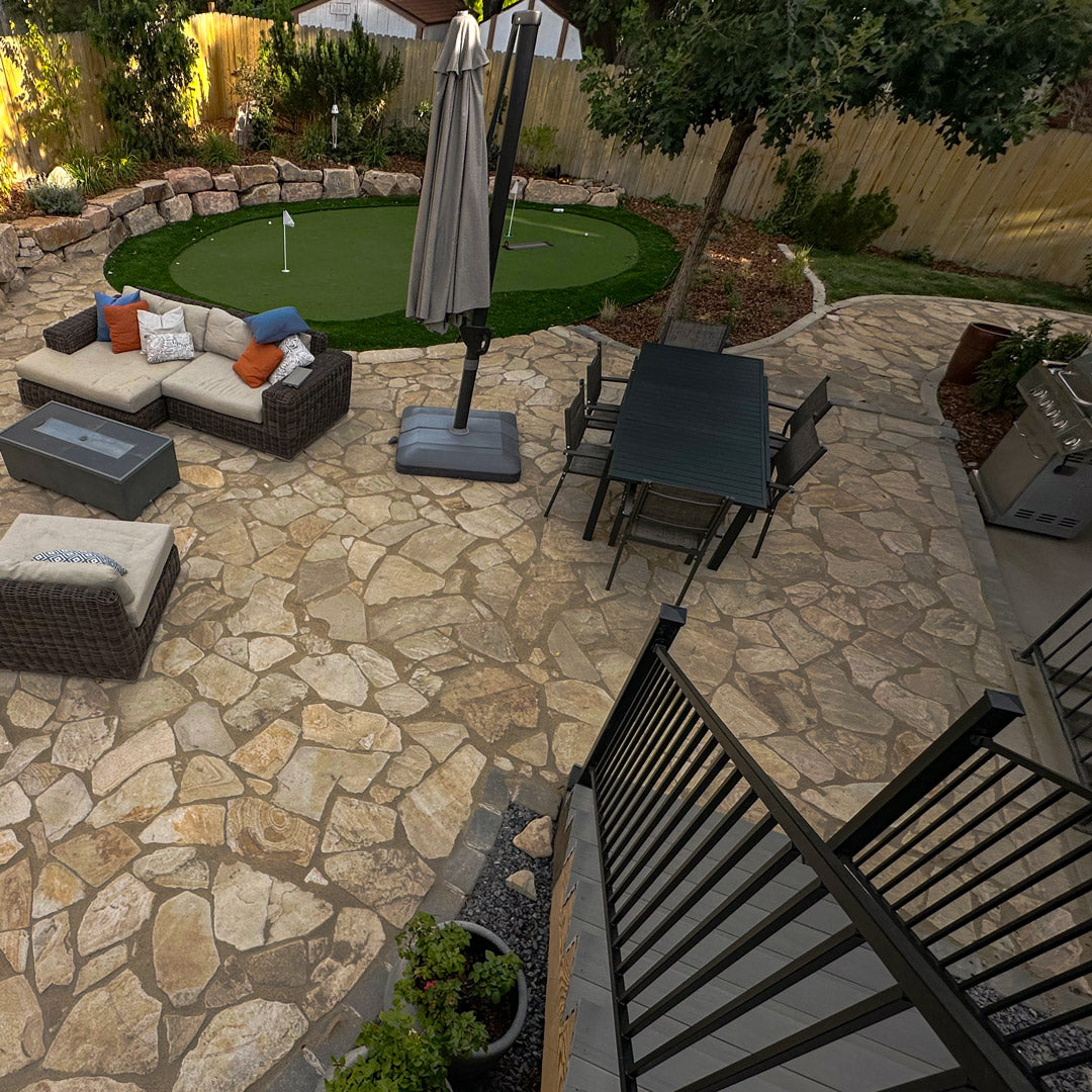 Outdoor stone patio with xeriscaped lawn elements and artificial turf putting green