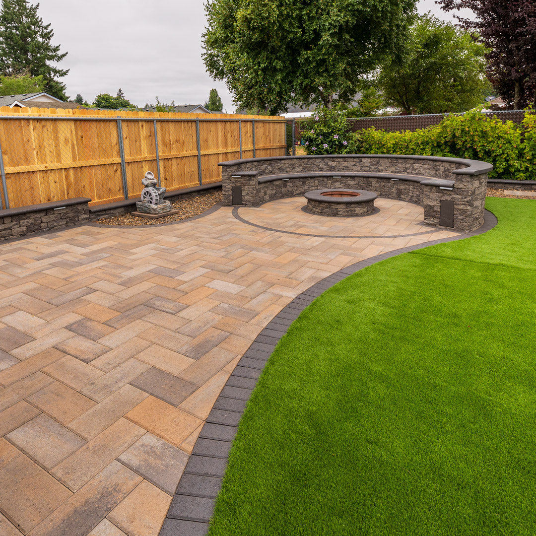 Paved patio with stone seating area, fire pit and artificial turf